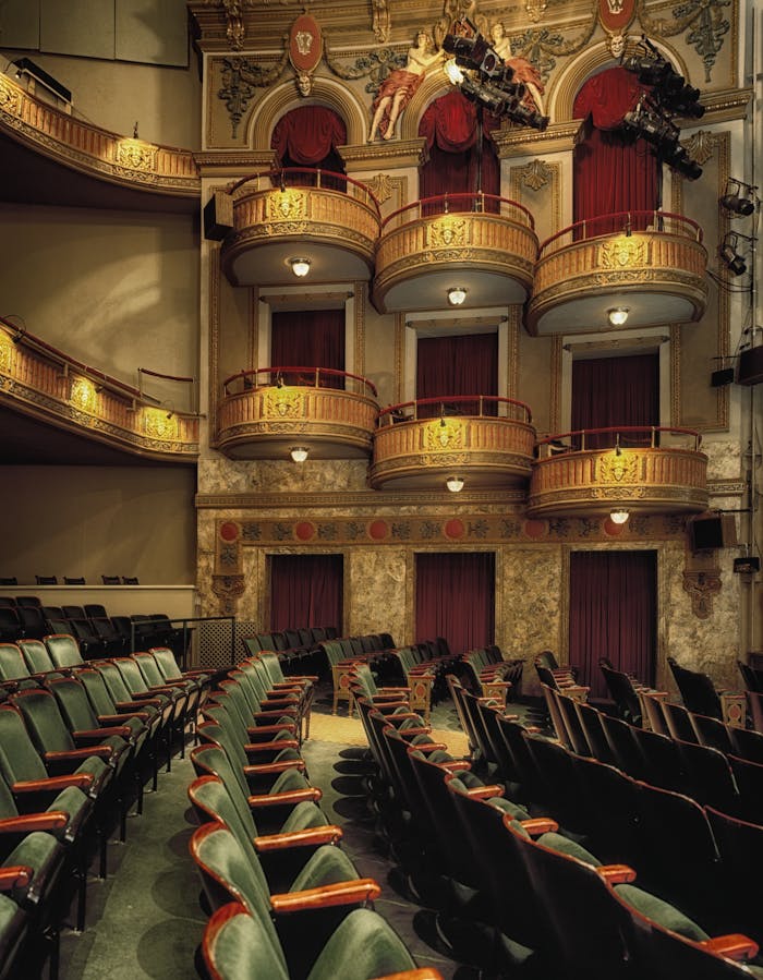 services-05 Classic theater interior featuring ornate balconies and empty seats, perfect for drama or performance themes.